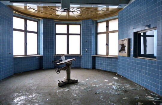 Runder, verlassener Raum mit blauen Fliesen.